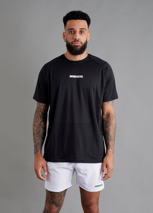 Male basketball model wearing ONCOURTANTICS black performance t-shirt with small chest logo, paired with white shorts, front-facing against plain grey background.