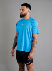 Side view of male basketball model wearing ONCOURTANTICS blue performance t-shirt, showing athletic fit and short sleeves, styled with black shorts.