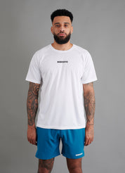 Male basketball model wearing ONCOURTANTICS White performance t-shirt with small chest logo, paired with teal shorts, front-facing against plain grey background.