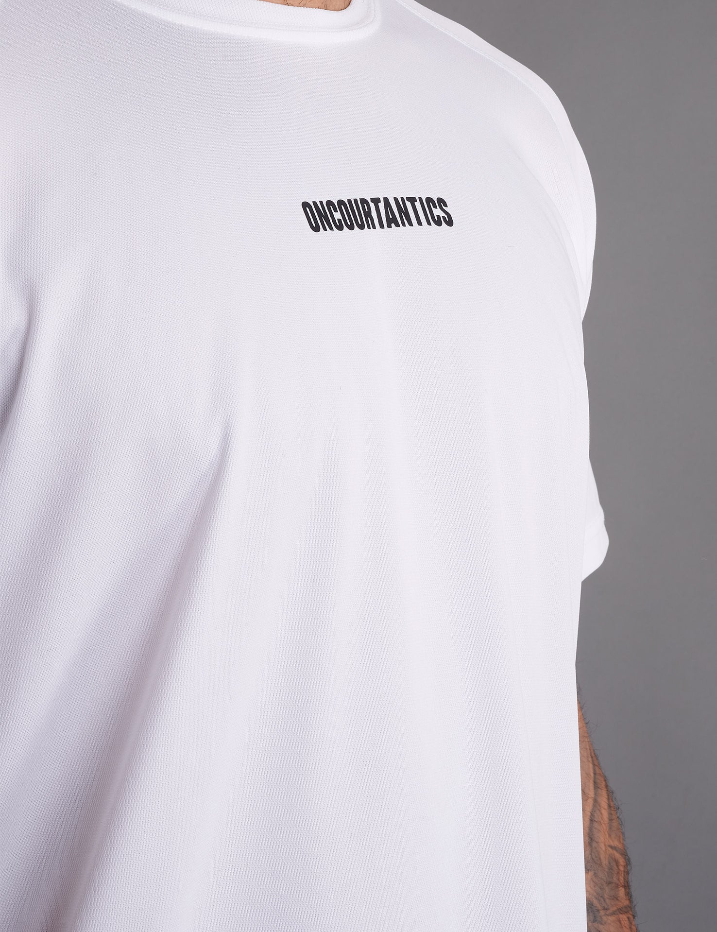 Close-up of ONCOURTANTICS White performance t-shirt fabric and small chest logo detail, highlighting lightweight, breathable material.